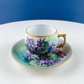 Porcelain tea cup and saucer with hand-painted violet flowers and green leaves