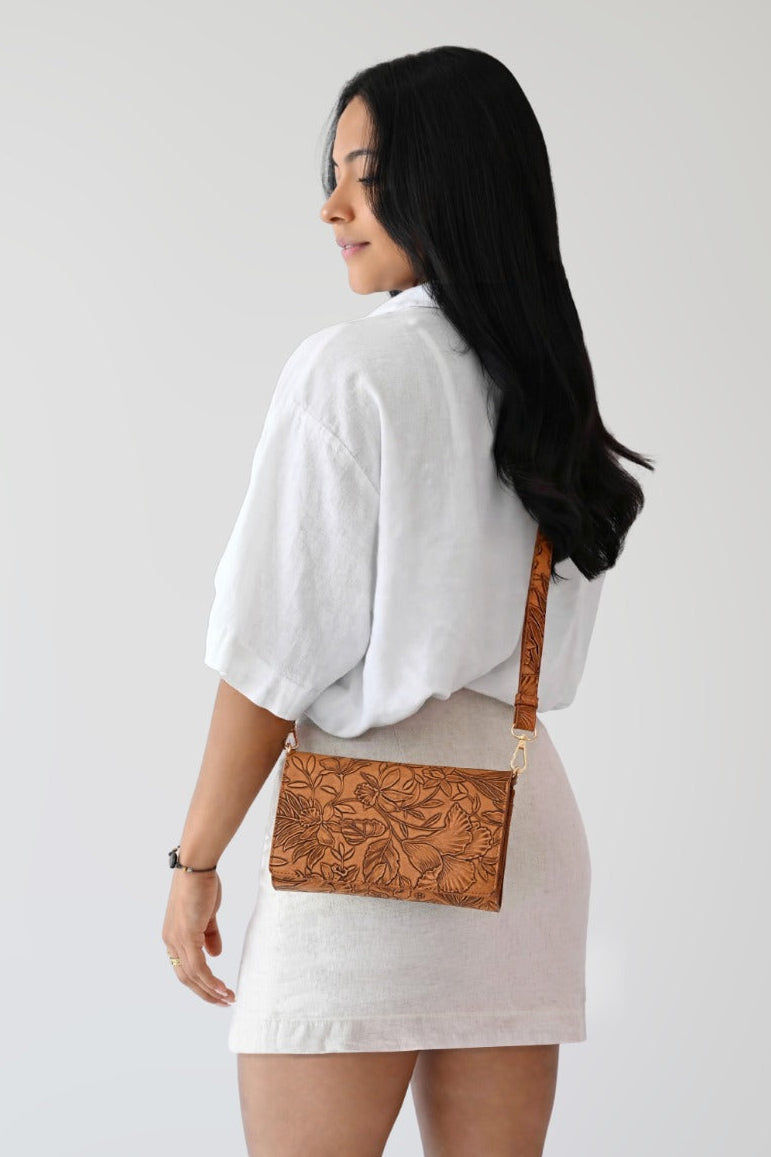 Rust floral RFID crossbody wallet worn across shoulder on model
