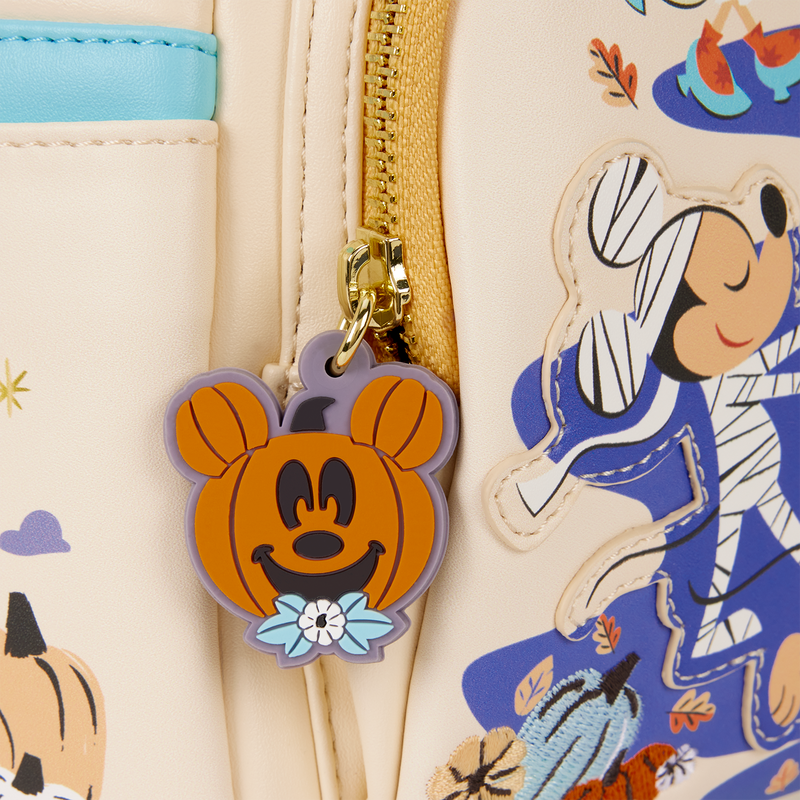 Close-up of cream mini backpack zipper pull with Mickey face charm; blue trim