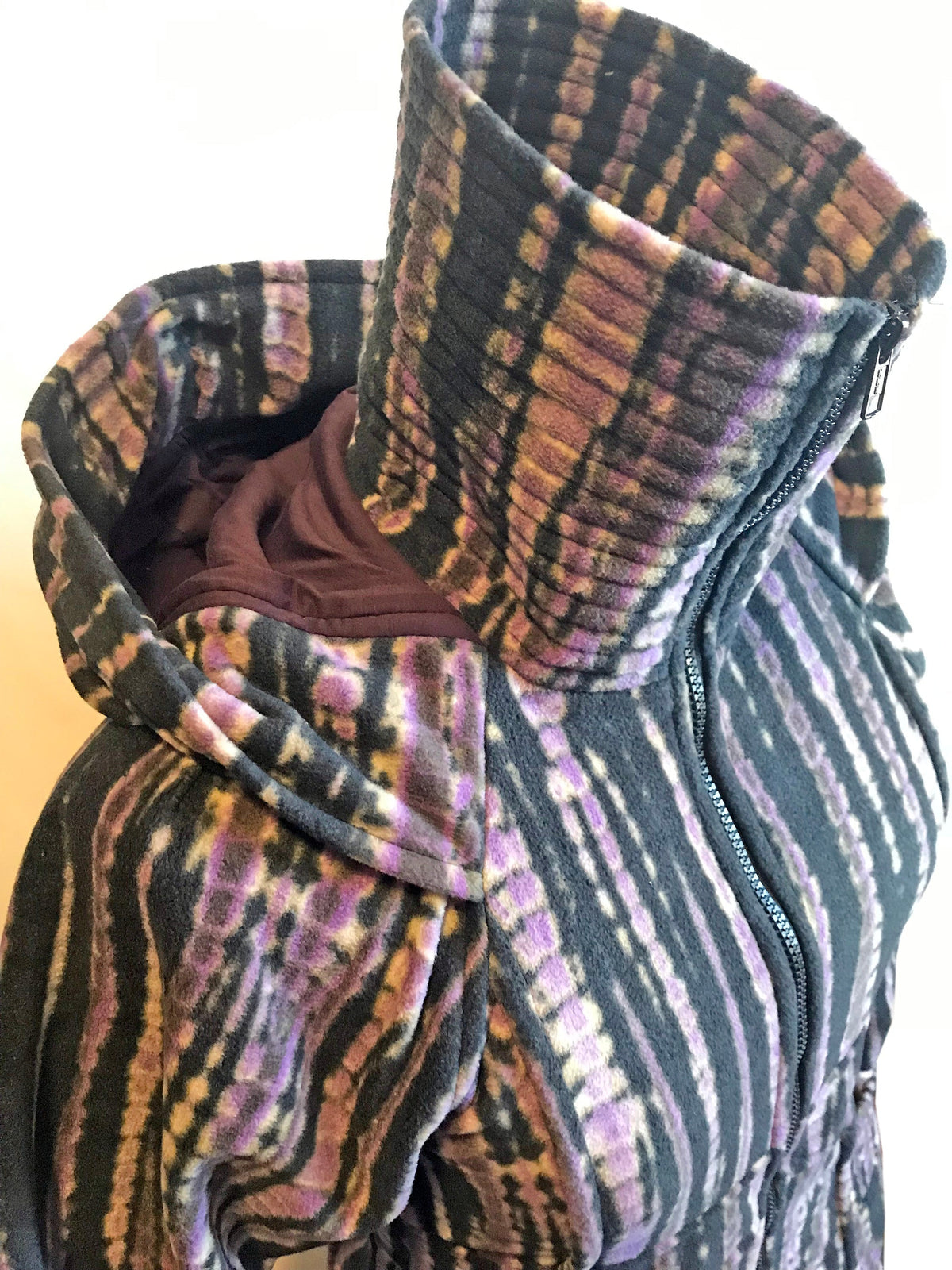 Close-up of fleece hooded sweater jacket, multi-color striped fabric and hood edge