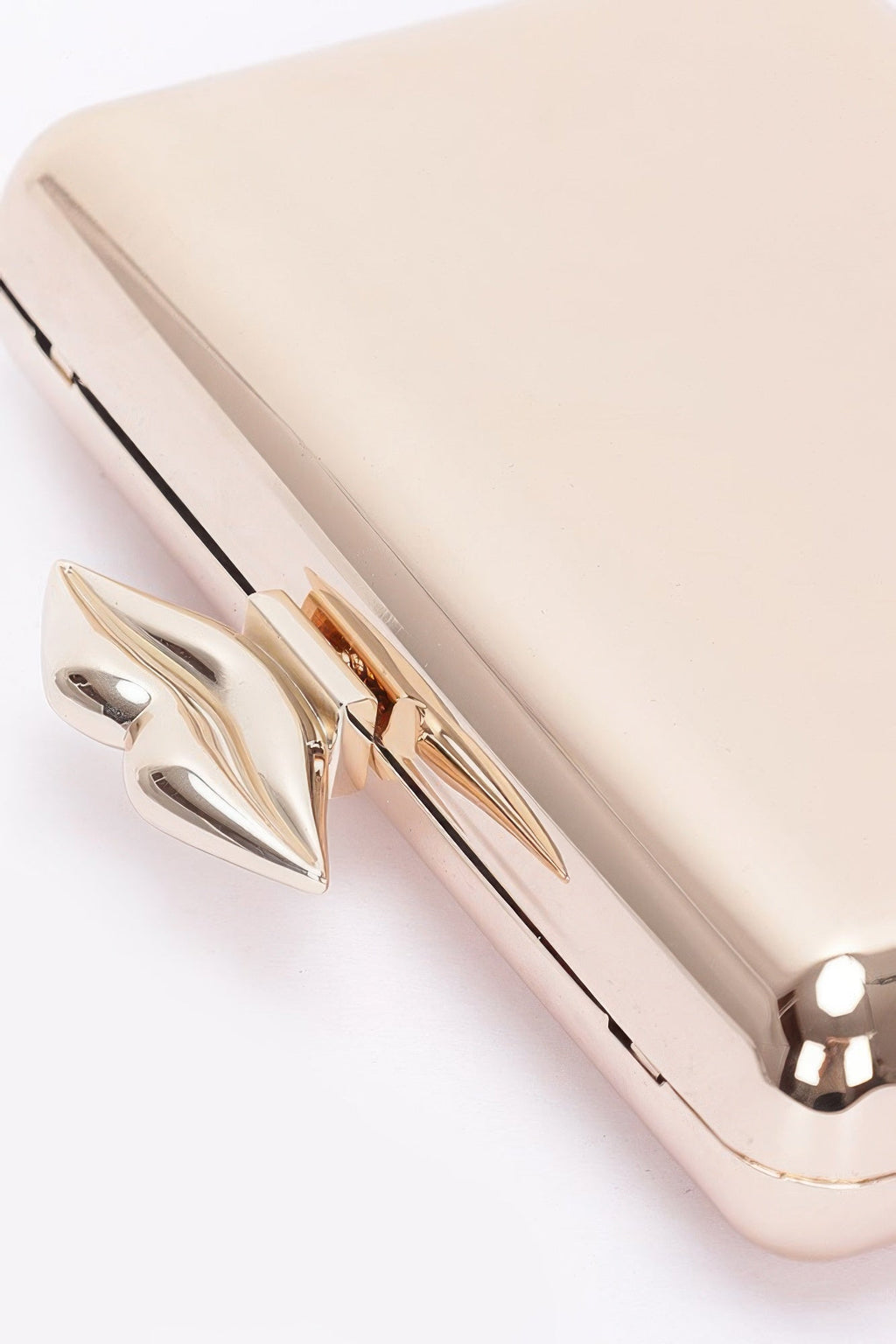 Close-up: gold-tone clasp on light beige clutch frame with hinge seam