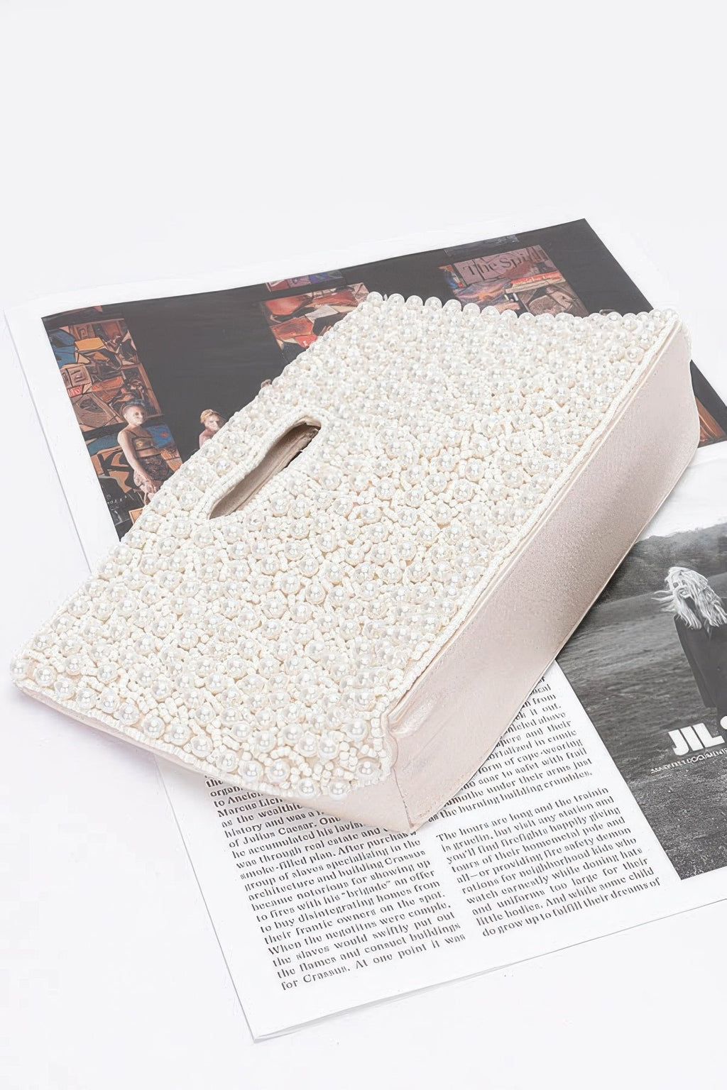 Cream beaded clutch bag with top handle, angled view