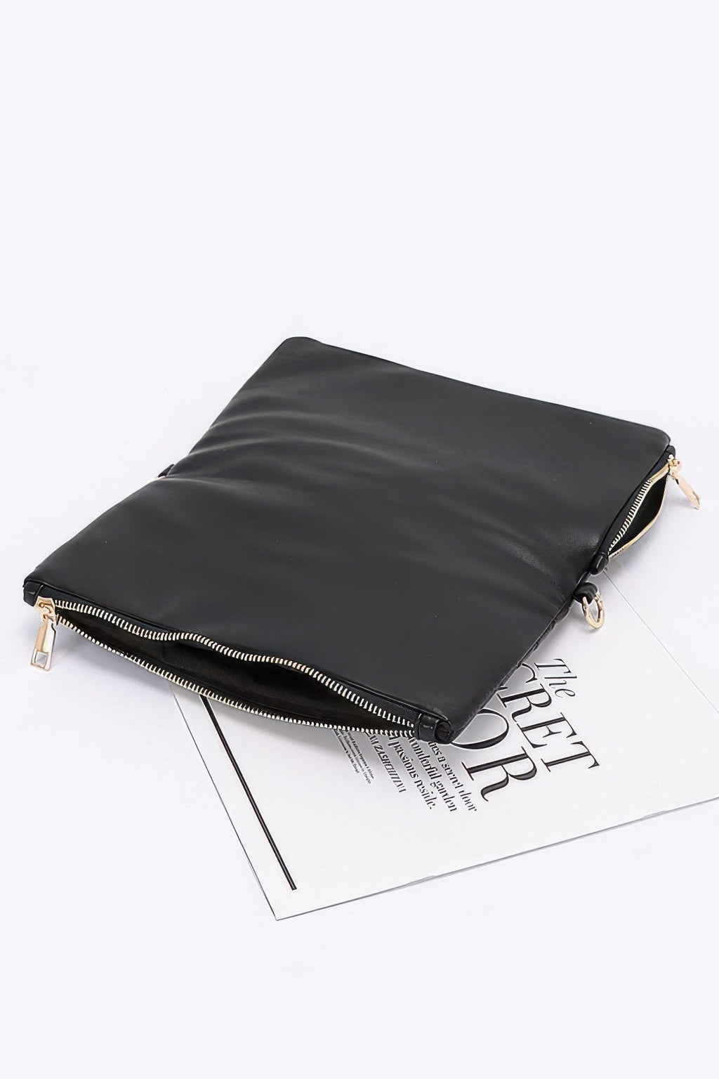 Black zip clutch with chain strap attachment and smooth back panel, gold-tone hardware