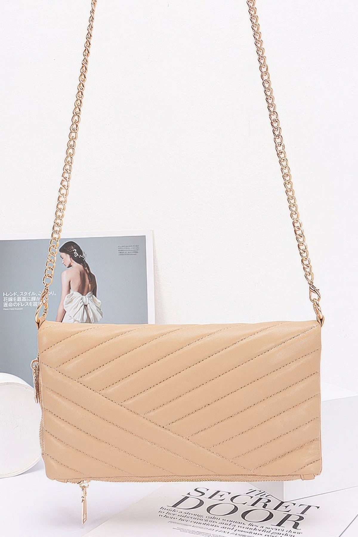Nude quilted clutch with long chain strap, gold-tone zipper and angled chevron stitching