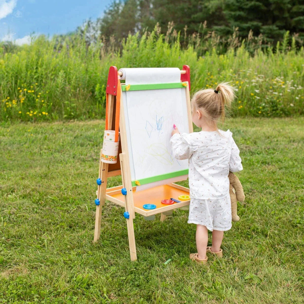 Kids art easel with whiteboard and tray, child drawing outdoors on grass, wooden frame