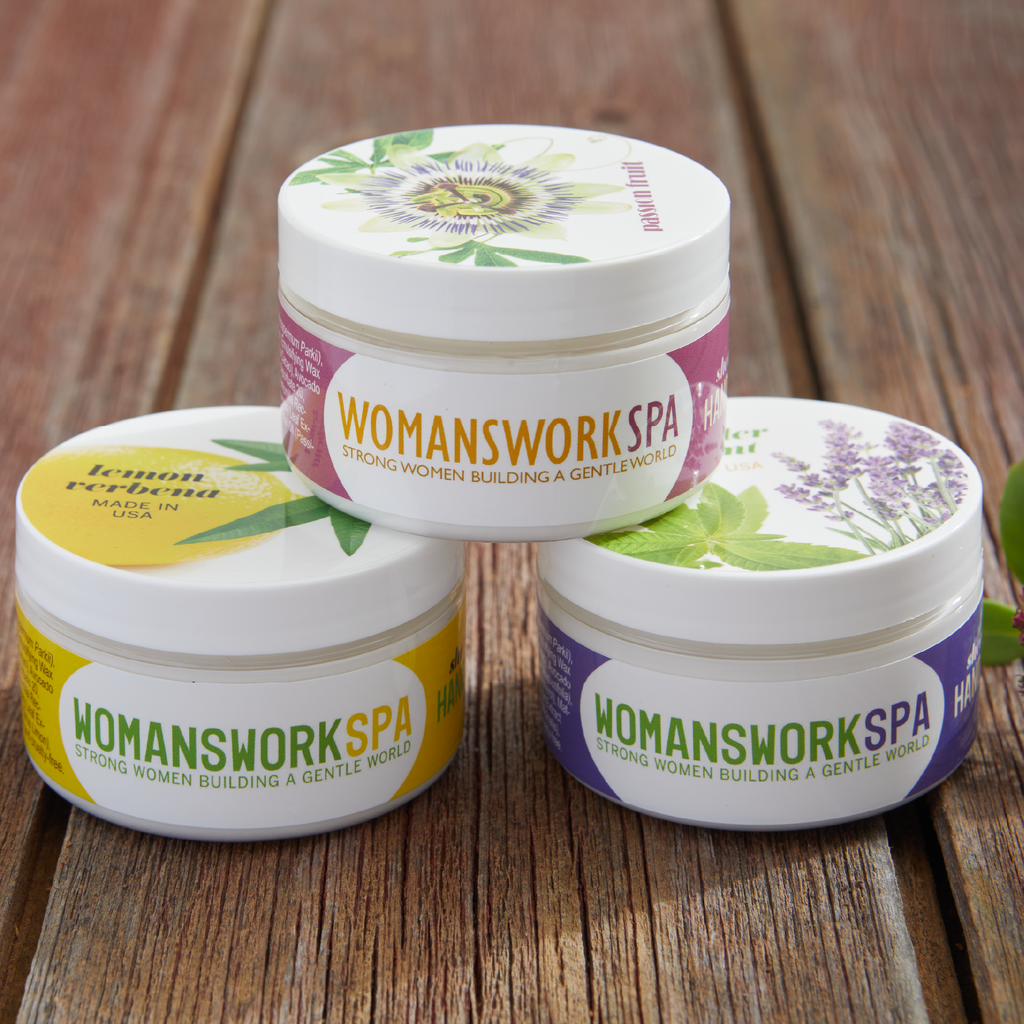 Three shea butter hand cream jars with botanical labels and WOMANSWORKSPA branding