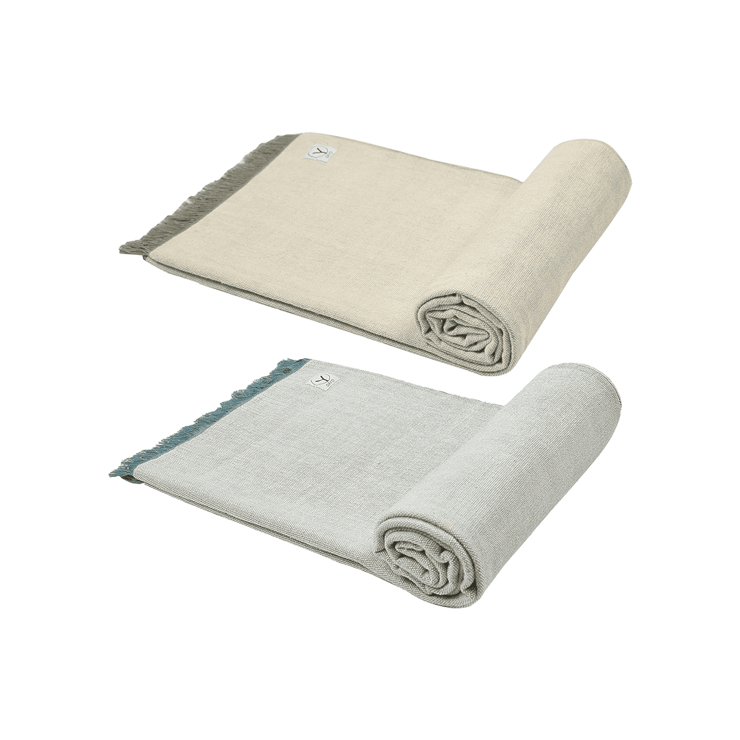 Light green yoga blanket with teal fringe, folded rolls and stitched hem detail.