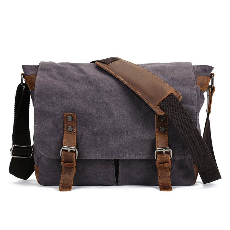 Waxed canvas crossbody bag in dark gray, front flap with two leather buckle straps and zipper.
