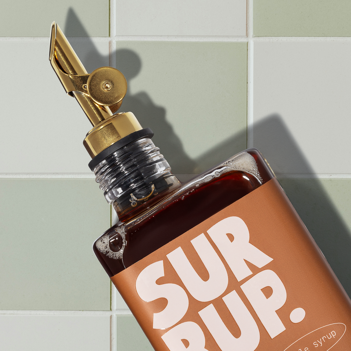 Cinnamon bun syrup bottle close-up with gold cap and SUR RUP label.