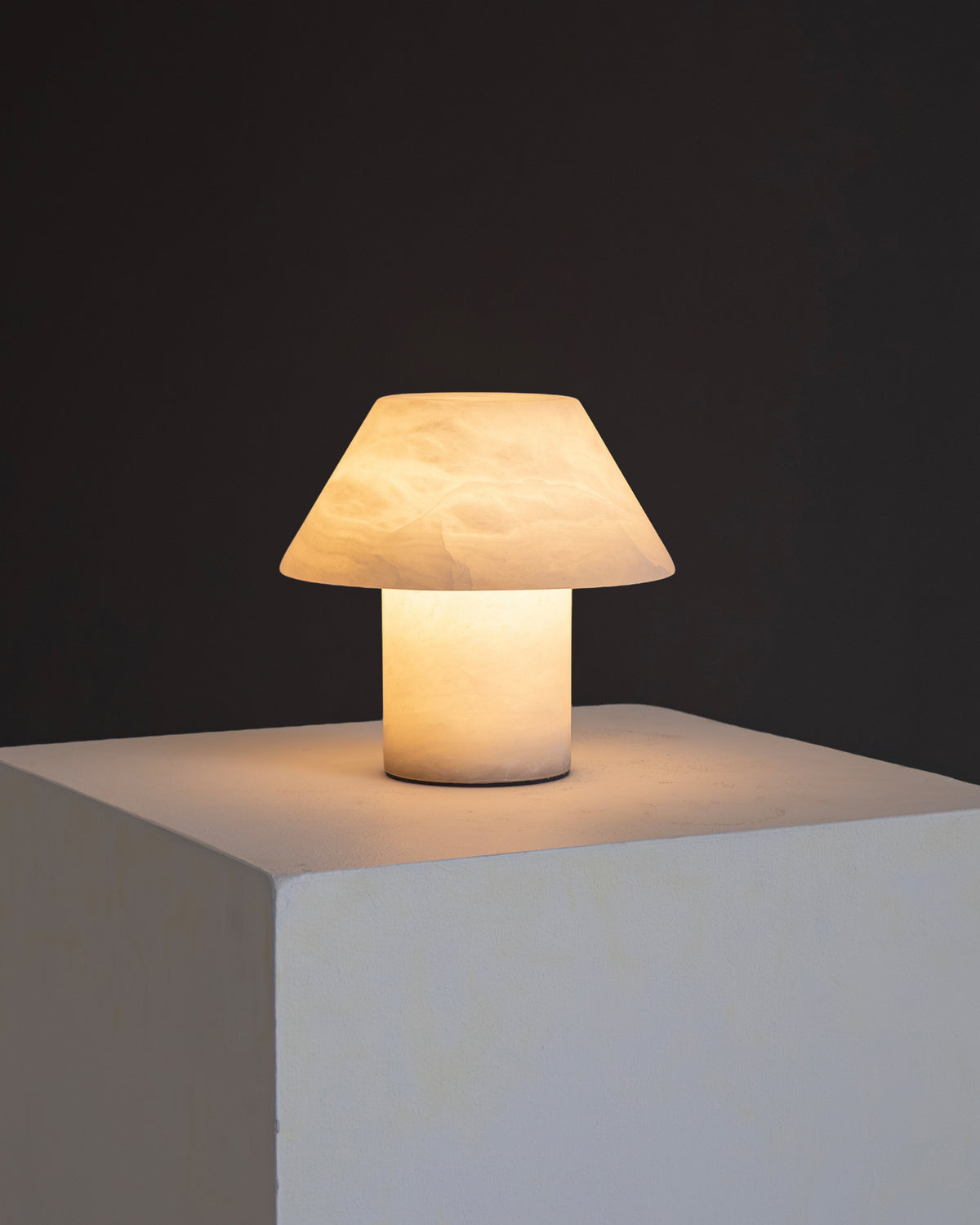 Cream table lamp with angled fabric shade and cylindrical base on a side table
