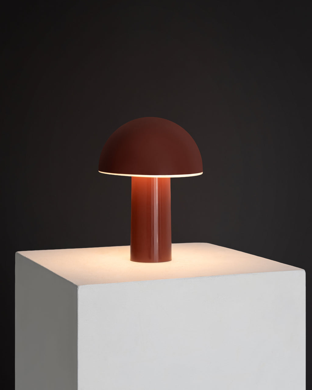 Burgundy portable lamp with dome shade and cylindrical base, warm glow