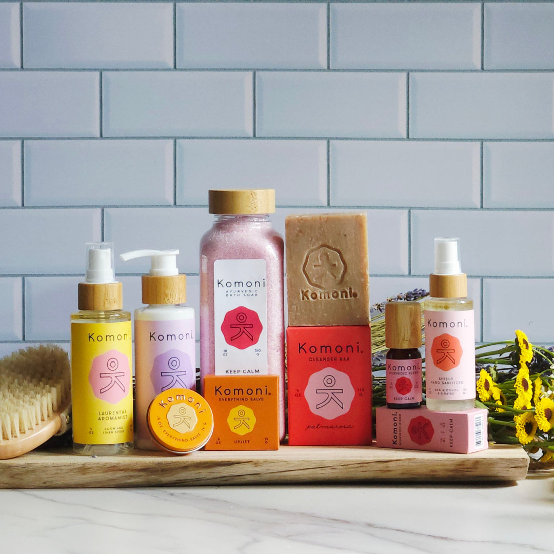 Skincare care package assortment with Komoni bottles, lotion pumps, and soap bars on shelf
