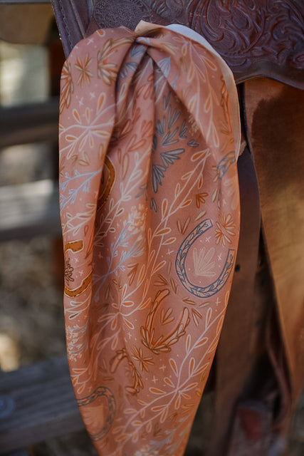 Dusty rose wild rag scarf with botanical sprigs and paisley pattern, draped close-up
