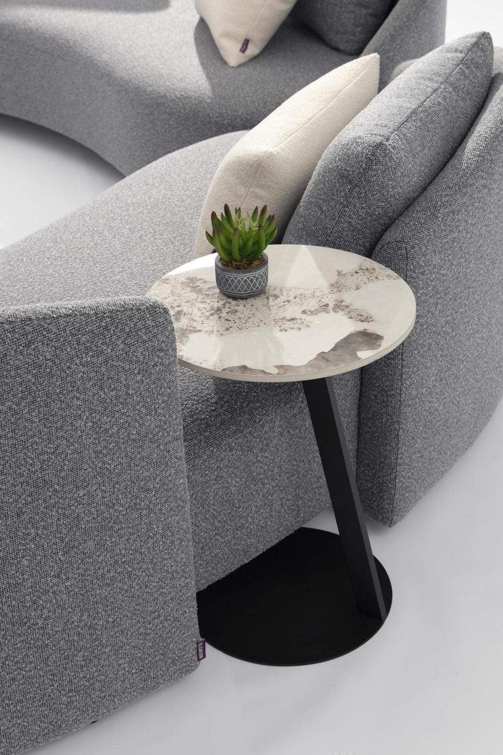 Gray outdoor lounge sofa with round side table and small potted plant