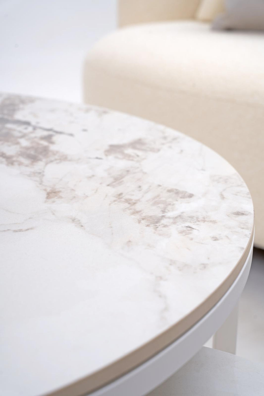 Round coffee table with white marble-look top and smooth light-gray side