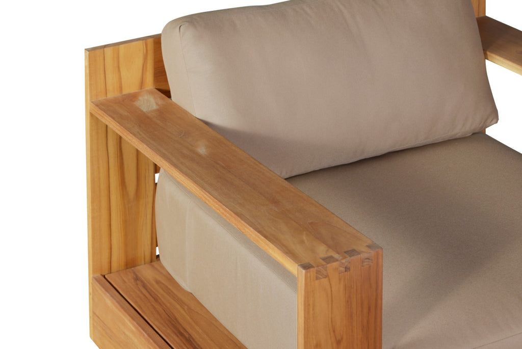 Teak armchair detail: beige cushion on armrest and slatted wood side panel.