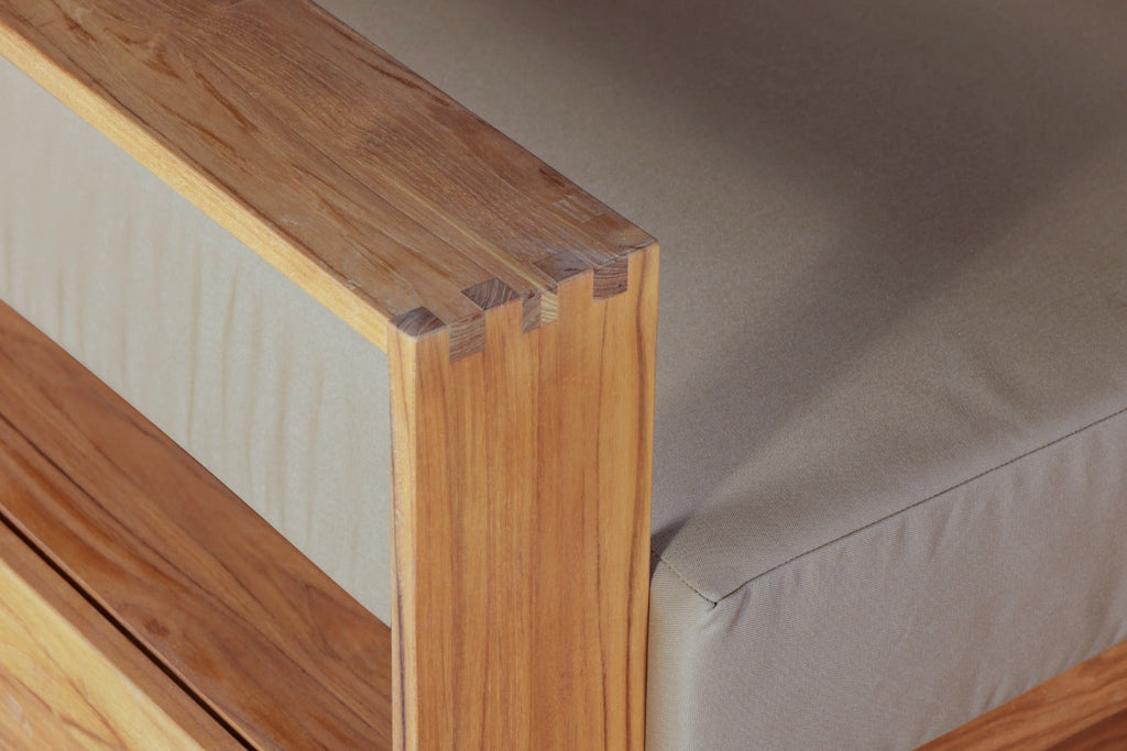 Teak chair frame detail showing joined wood slats and cushioned seat edge