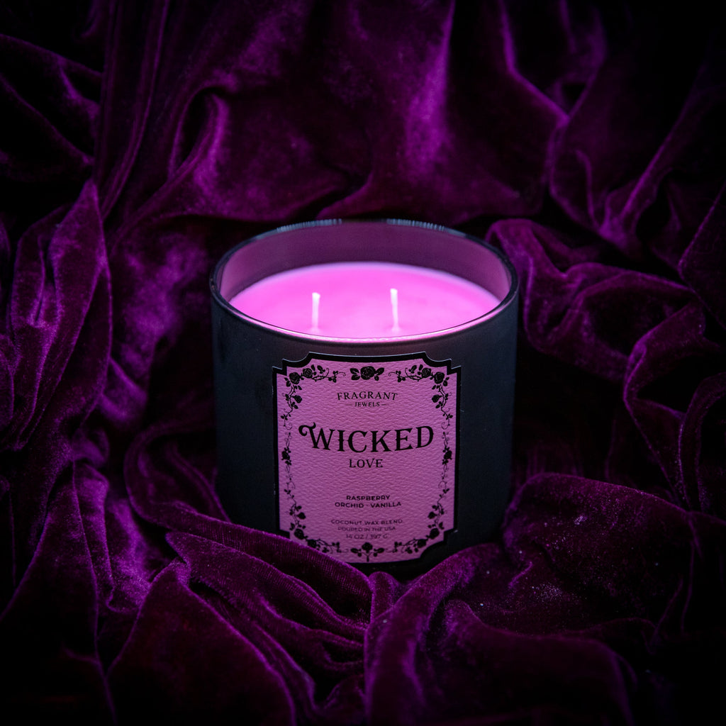 Black jewel candle jar with pink Wicked Love label and lit tealight