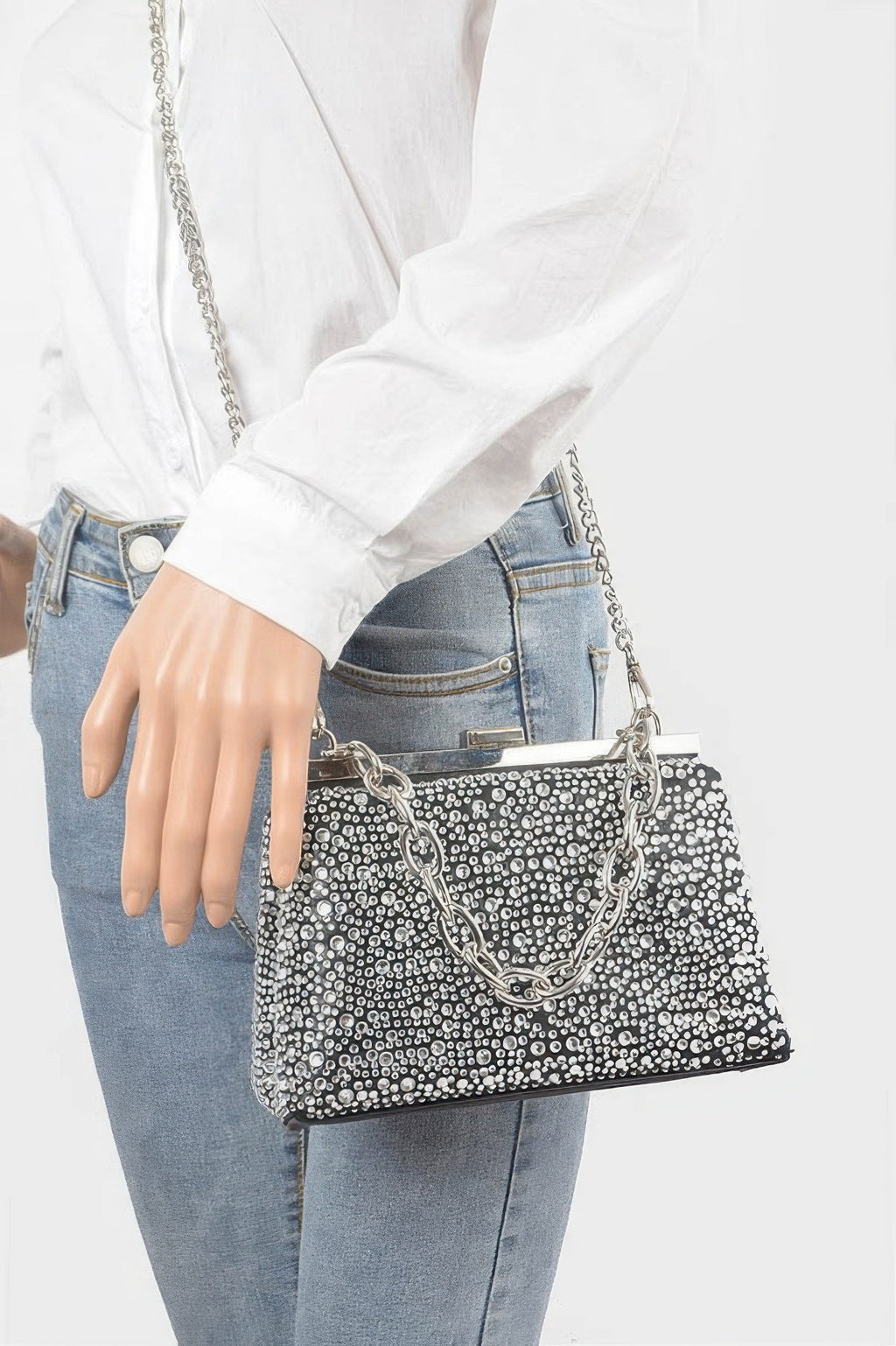 Rhinestone hotfix clutch on model with chain strap, black trim, held at side