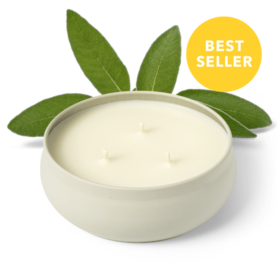 White 3-wick candle in round ceramic jar with green leaves, three flames visible
