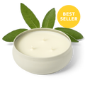 White 3-wick candle in round ceramic jar with green leaves, three flames visible