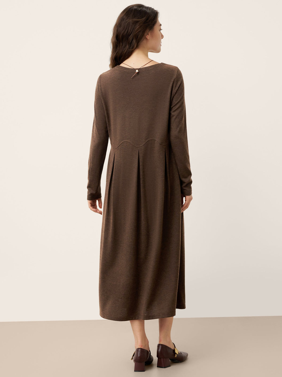 Brown wool midi dress back view with sculpted pleats and center-back seam detail.