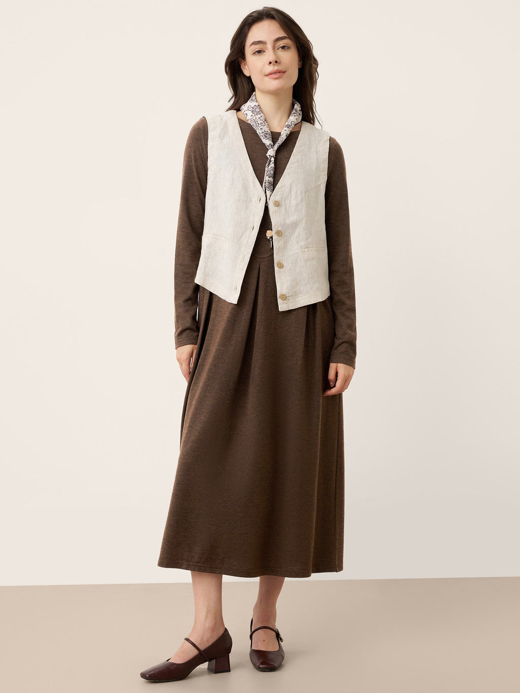 Brown wool midi dress with button front, shown with a cream sleeveless vest overlay.