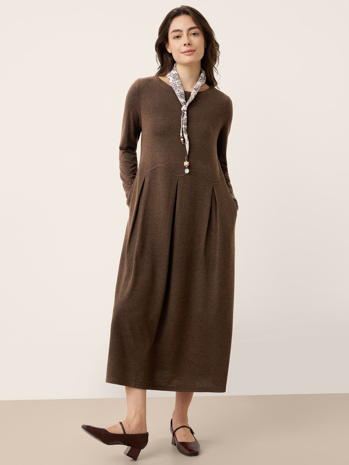 Brown wool midi dress with sculpted pleats, button front, and curved arc-panel seams.