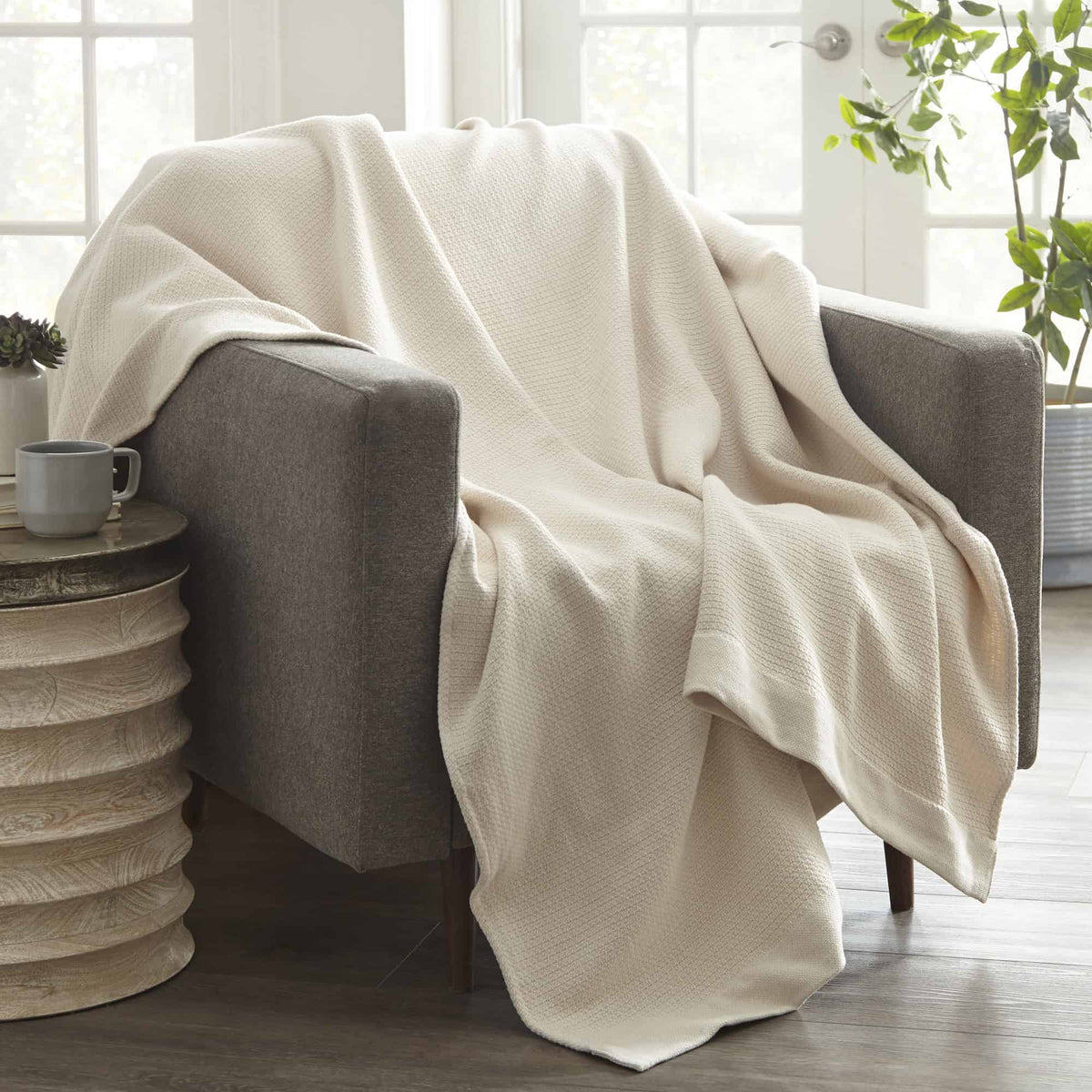 White woven blanket draped over an armchair with soft folds.
