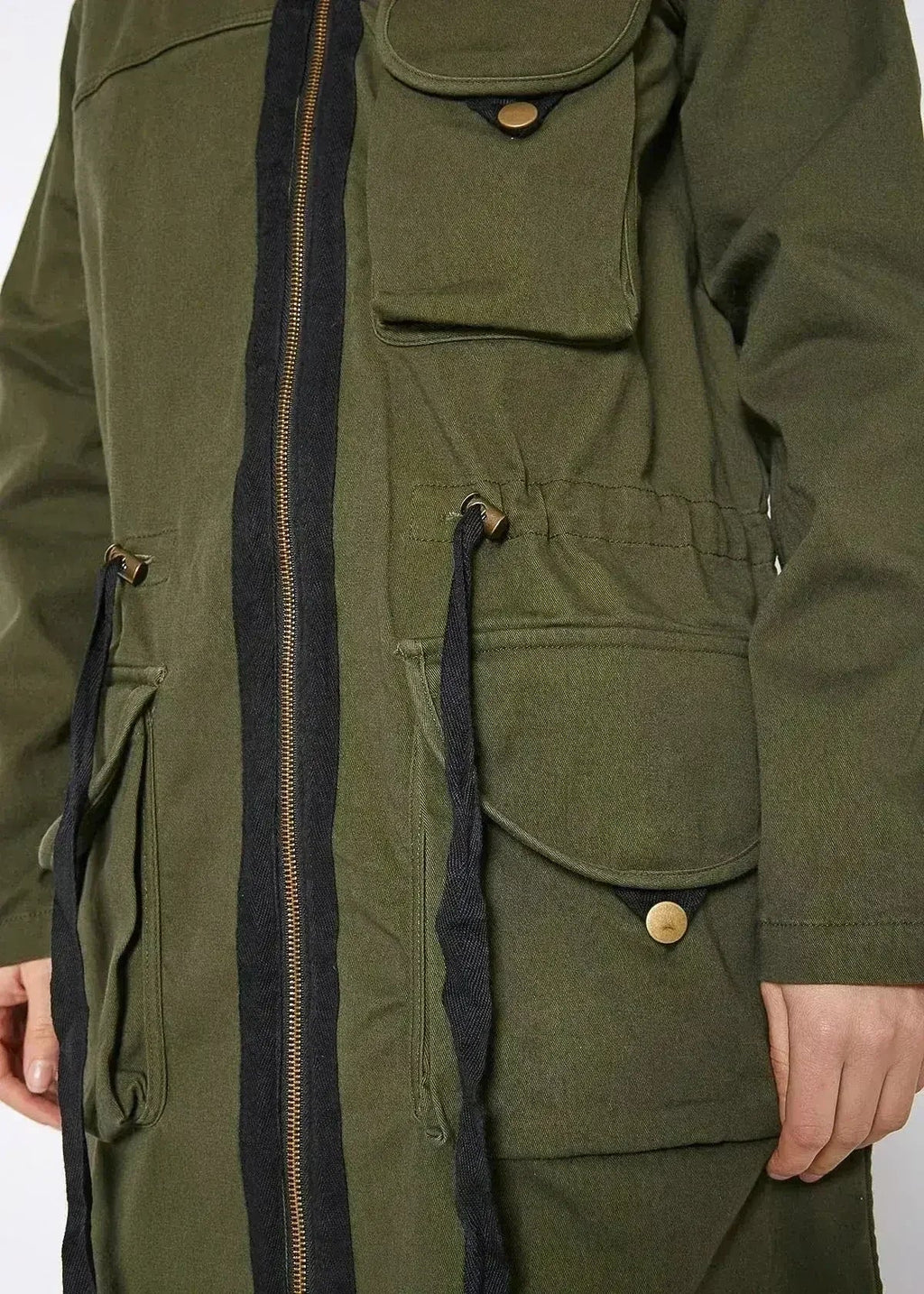 Olive utility jacket close-up showing front zipper, flap pockets, and drawcord