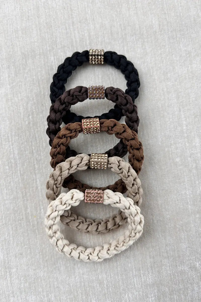 Stacked braided hair ties in black, brown, and cream with jeweled center bead blocks.