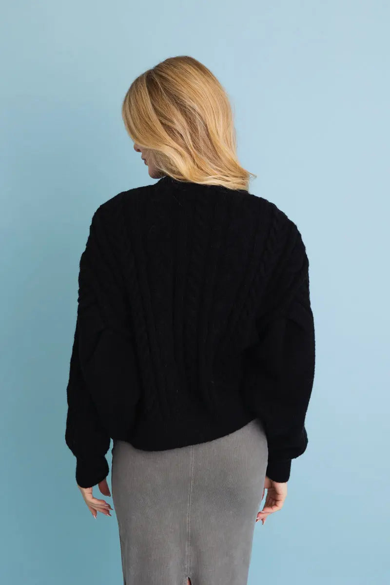 Black cropped cable-knit button-up cardigan, back view with chunky cable pattern