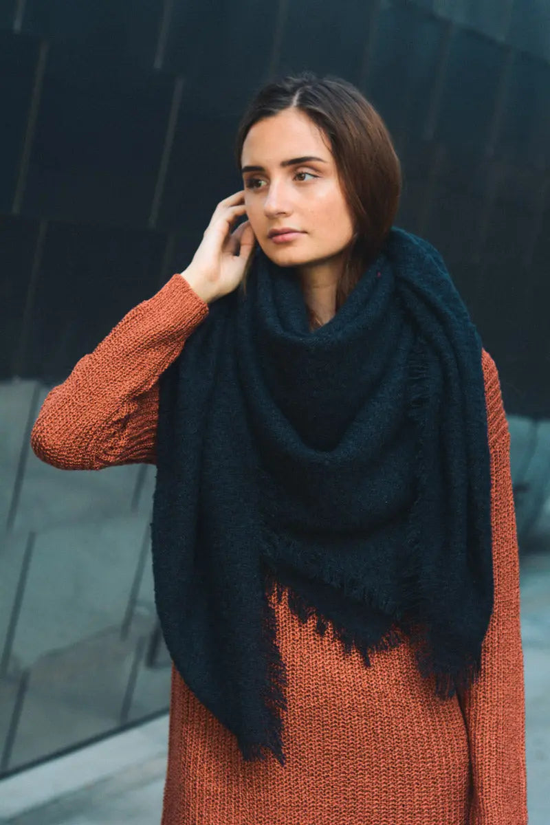 Deep blue plush mohair square scarf, draped around shoulders with fringe ends.