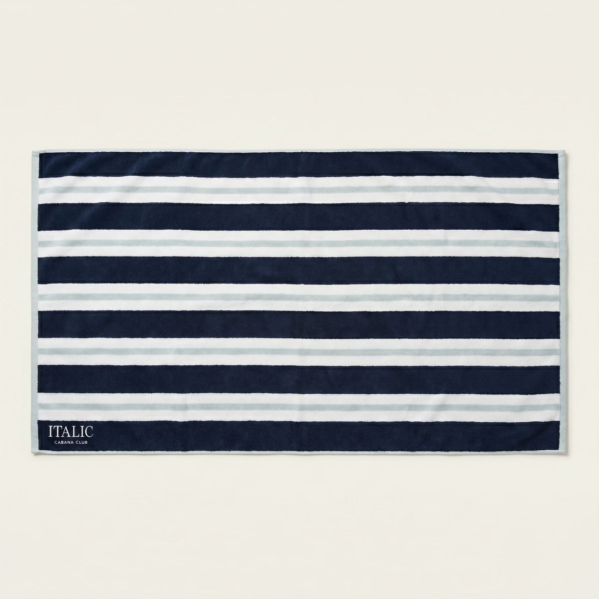Cotton beach towel with navy and white horizontal stripes and woven “ITALIC” label
