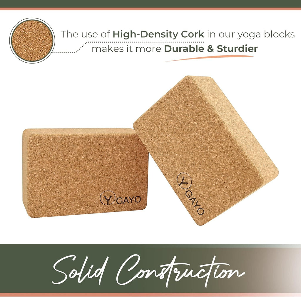 Two tan cork yoga blocks with Y-shaped logo on flat surfaces