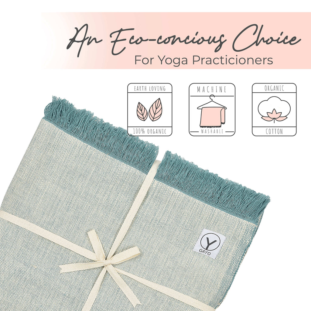 Light yoga blanket with teal tassel fringe and woven logo patch at corner.