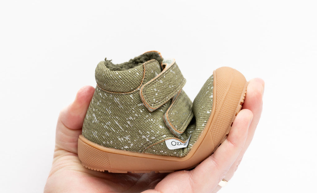 Toddler hiker boot held in hand, olive speckled fabric, sherpa lining, Velcro strap