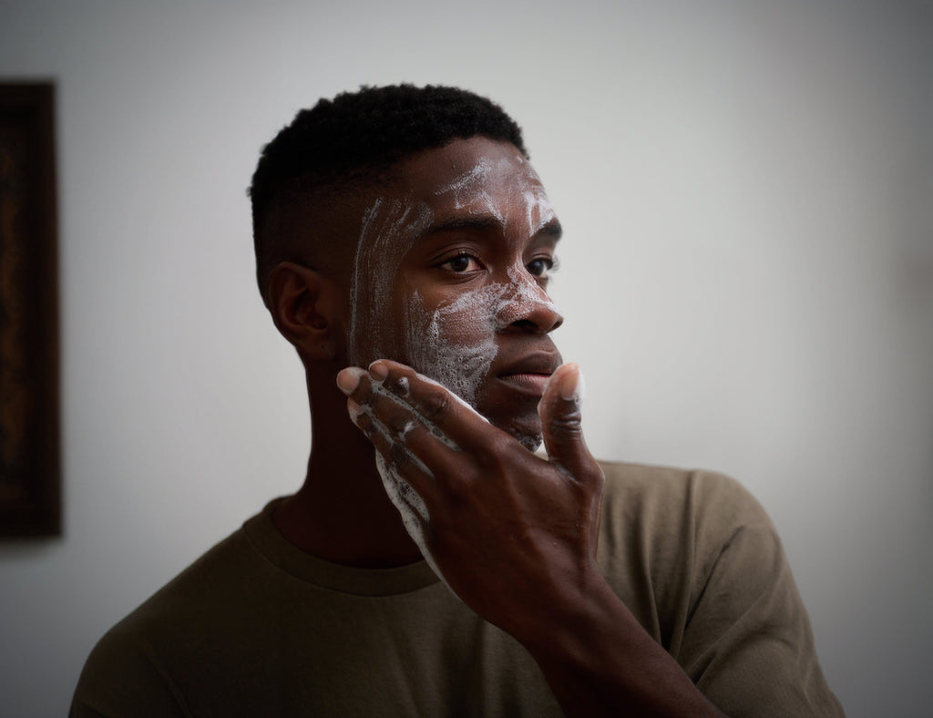 Man applying cleansing bar lather to face with hands