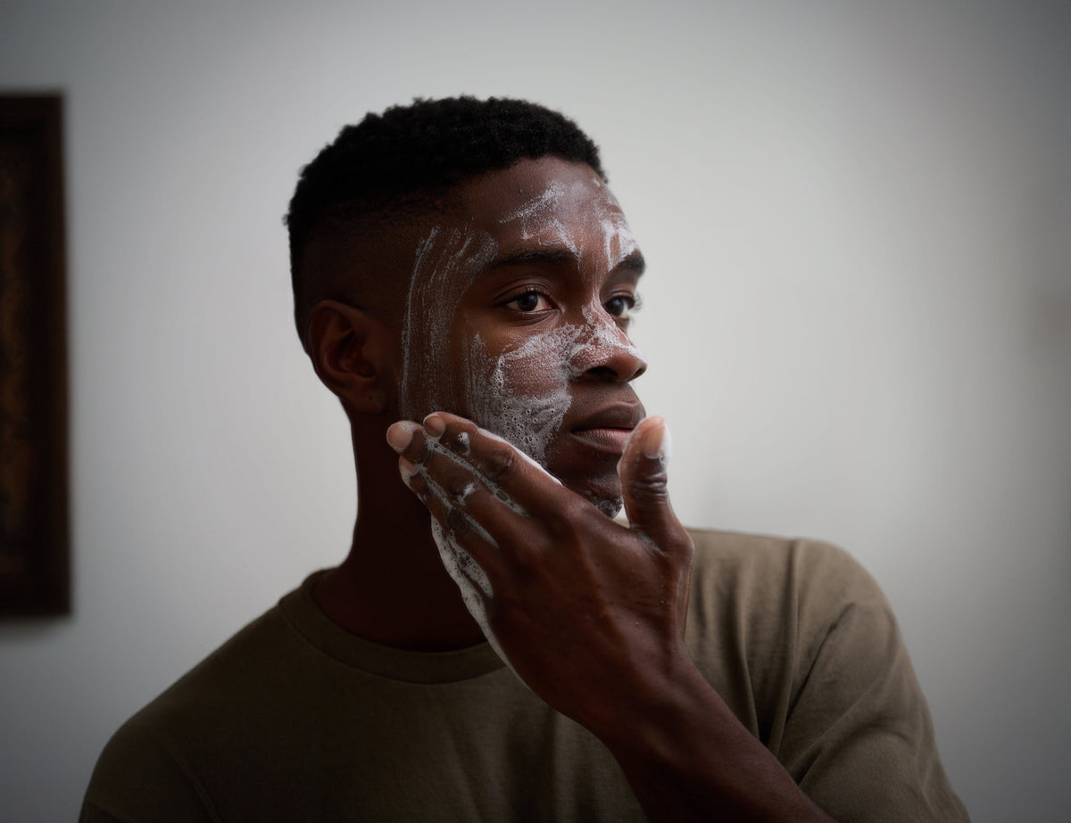 Man applying cleansing bar lather to face with hands