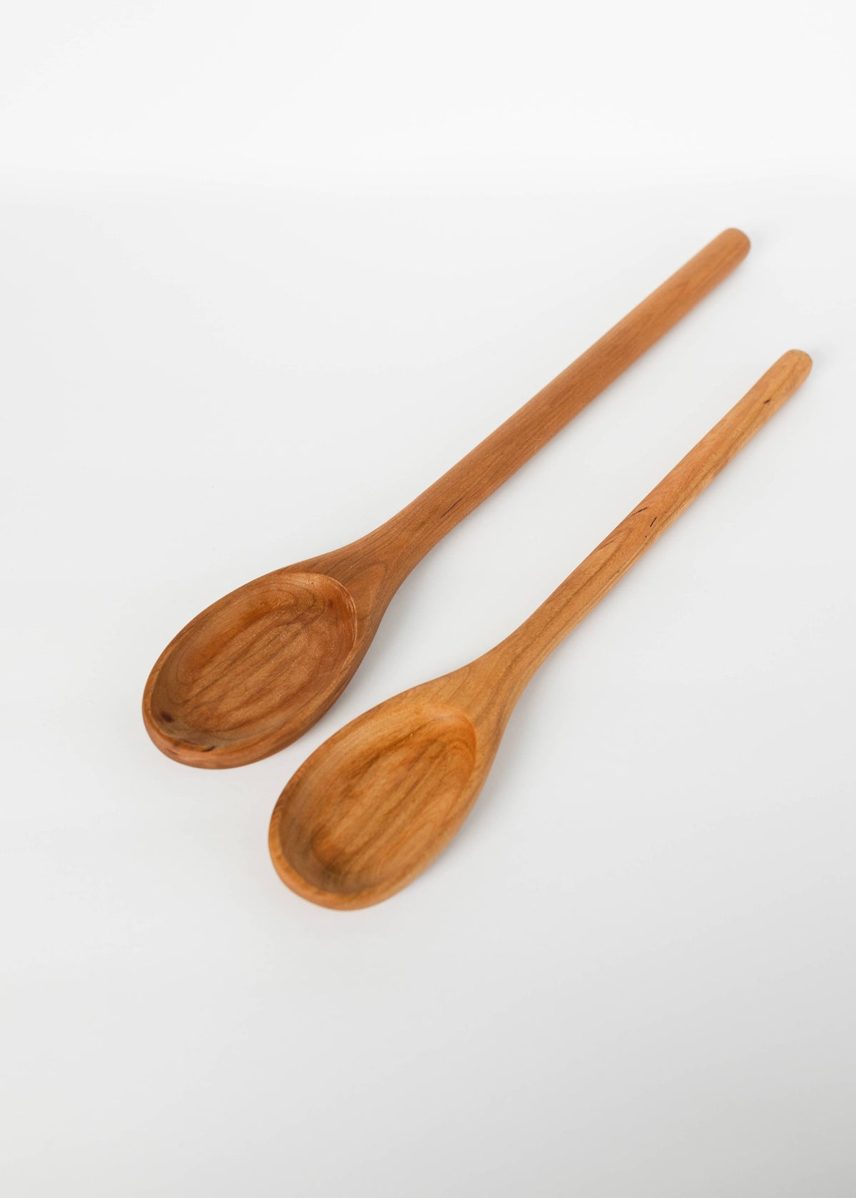 Two medium-brown wooden spoons with oval bowls and long handles.