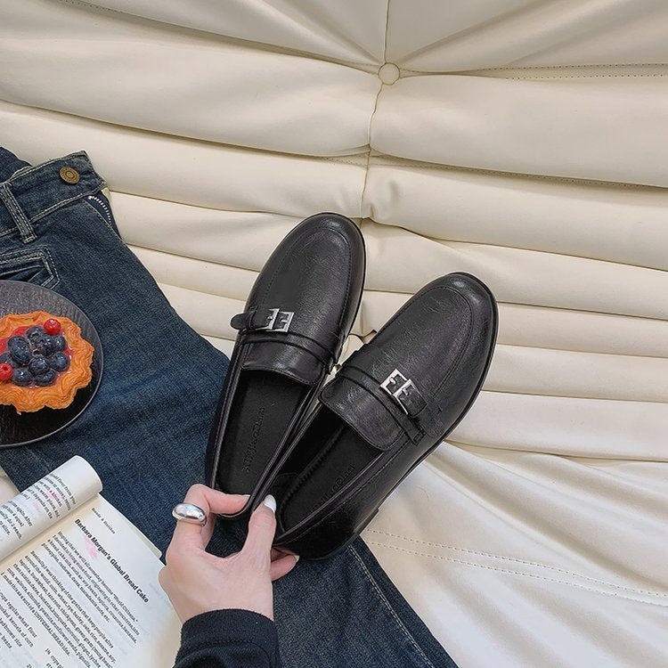 Black women's loafers with metal buckle and decorative F plate, flat low heel.