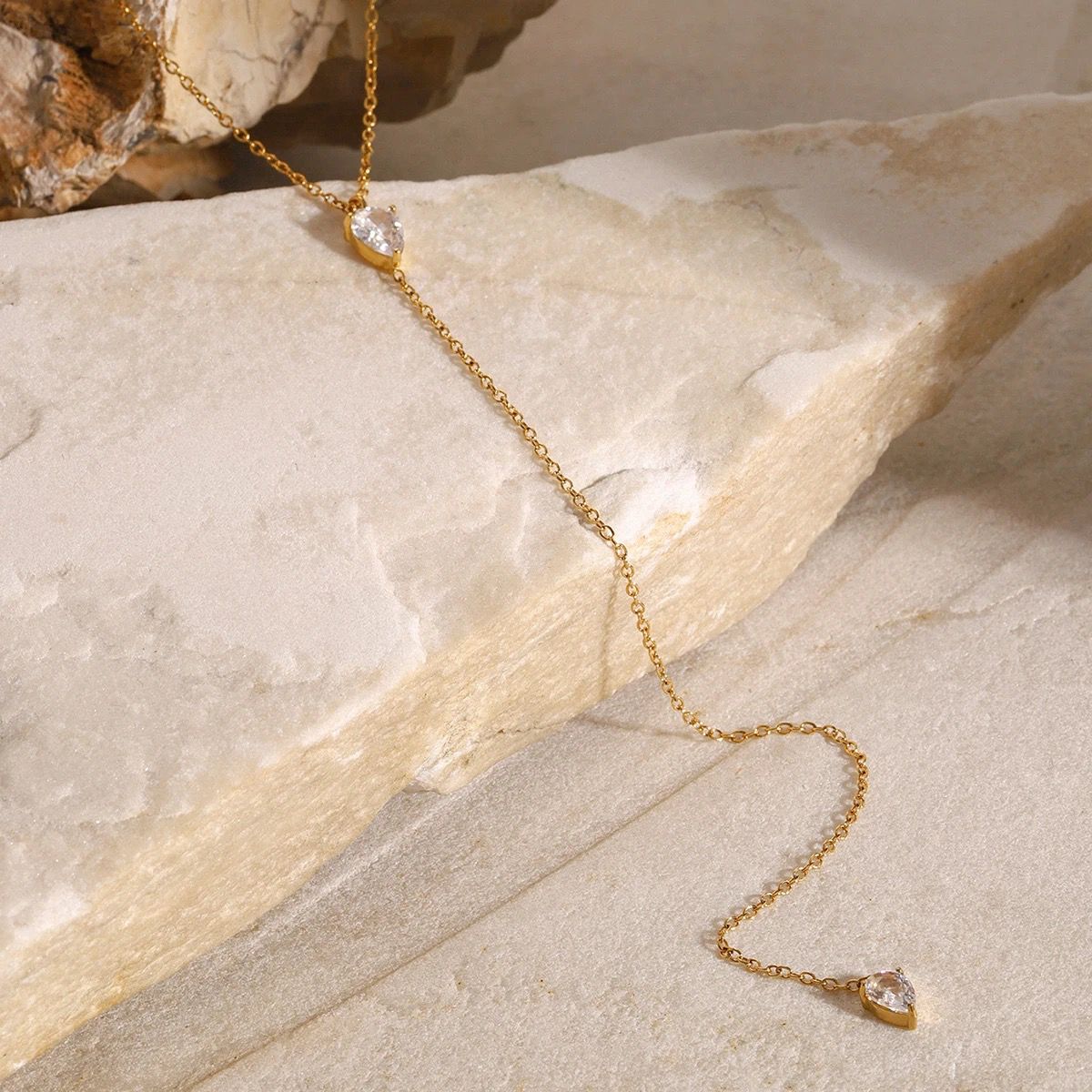 Gold-tone necklace with teardrop crystal pendant on long chain