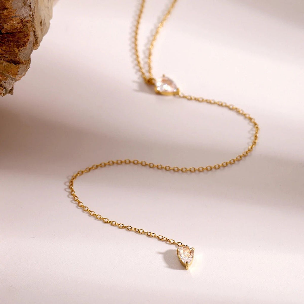 Gold-tone necklace with a dangling faceted teardrop crystal charm