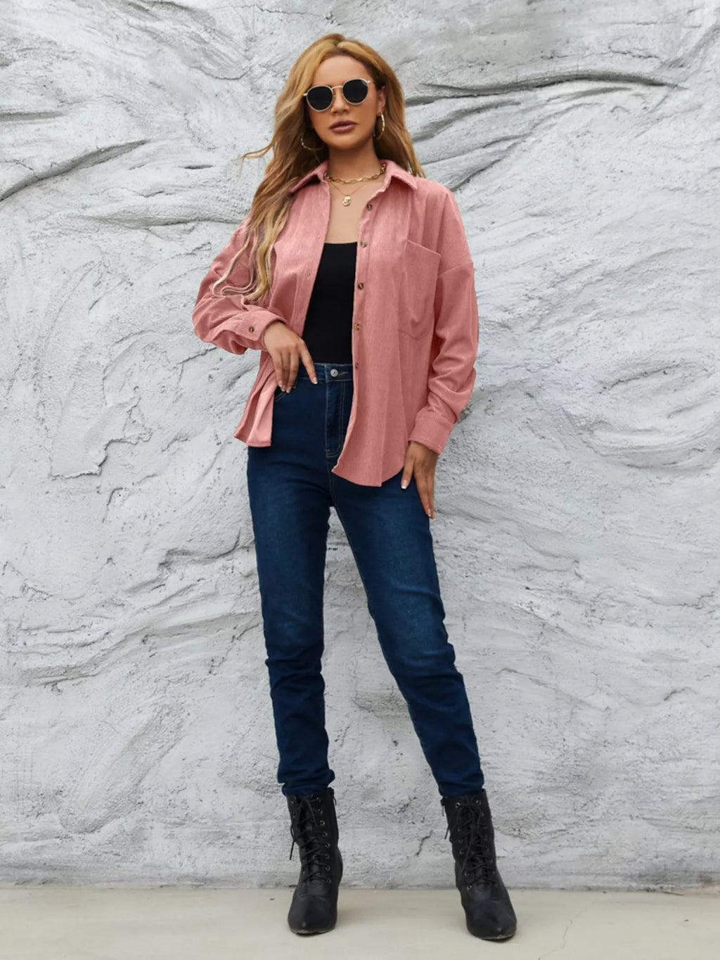 Pink corduroy button-front shirt worn with dark jeans and black ankle boots