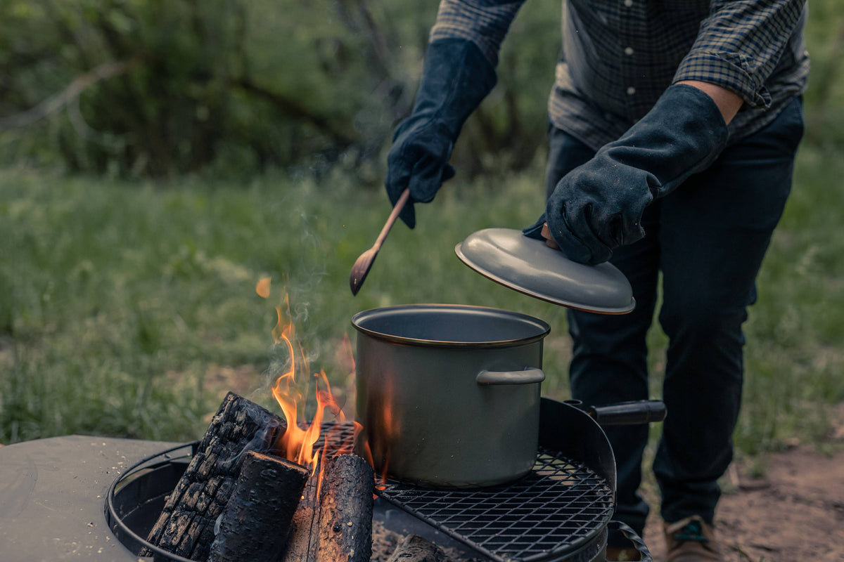Outdoor enamel stock pot on a grill with flames, dark gray pot and lid