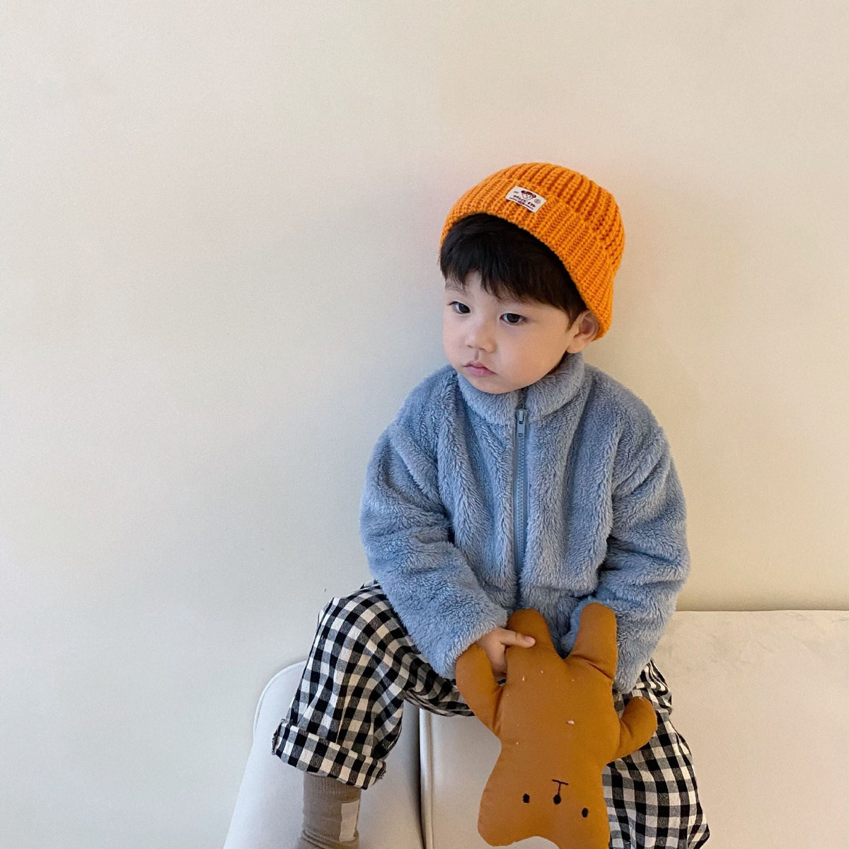Light grey kids fleece zip jacket with hood, worn with an orange knit beanie.