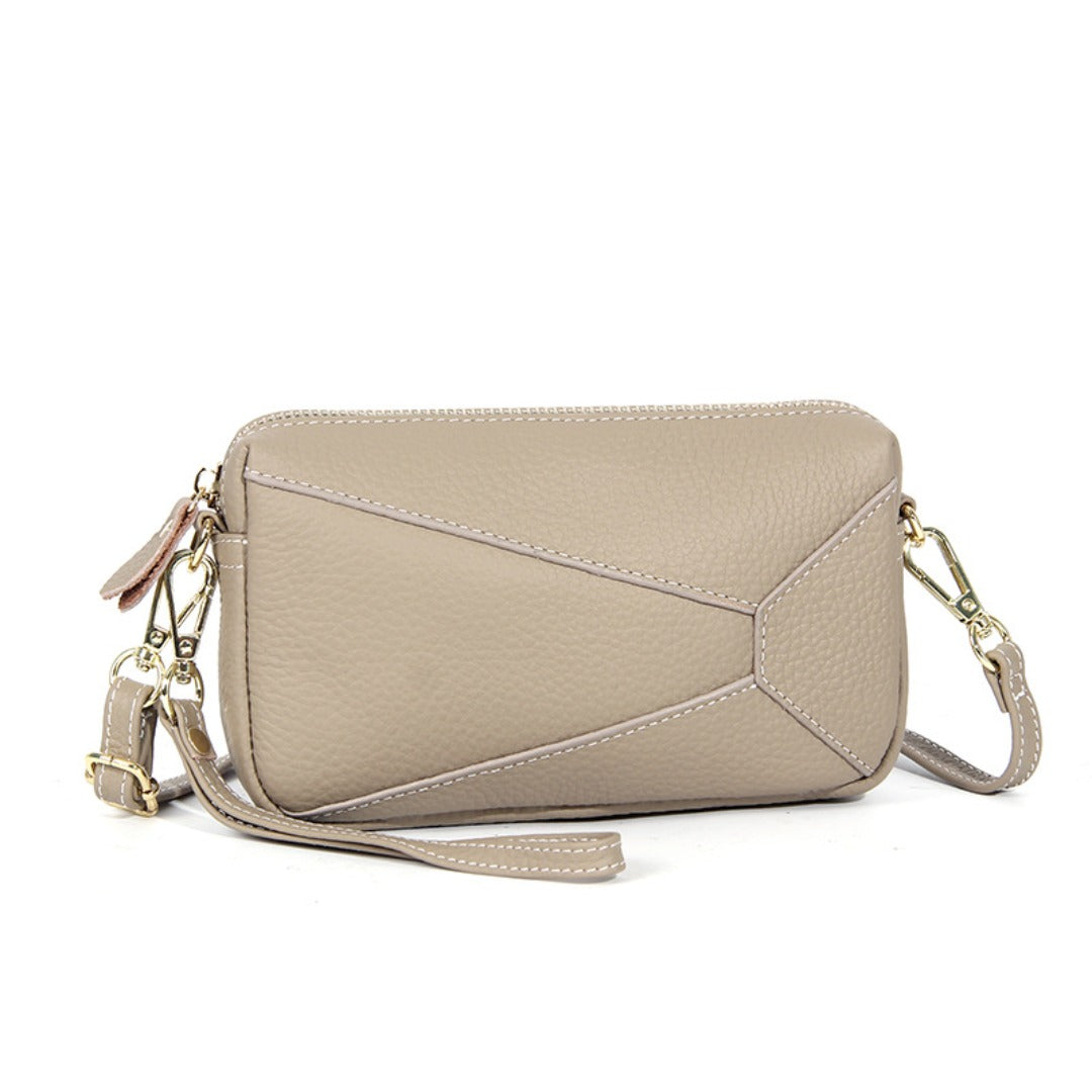 Light beige leather wristlet crossbody bag with zip top and shoulder strap