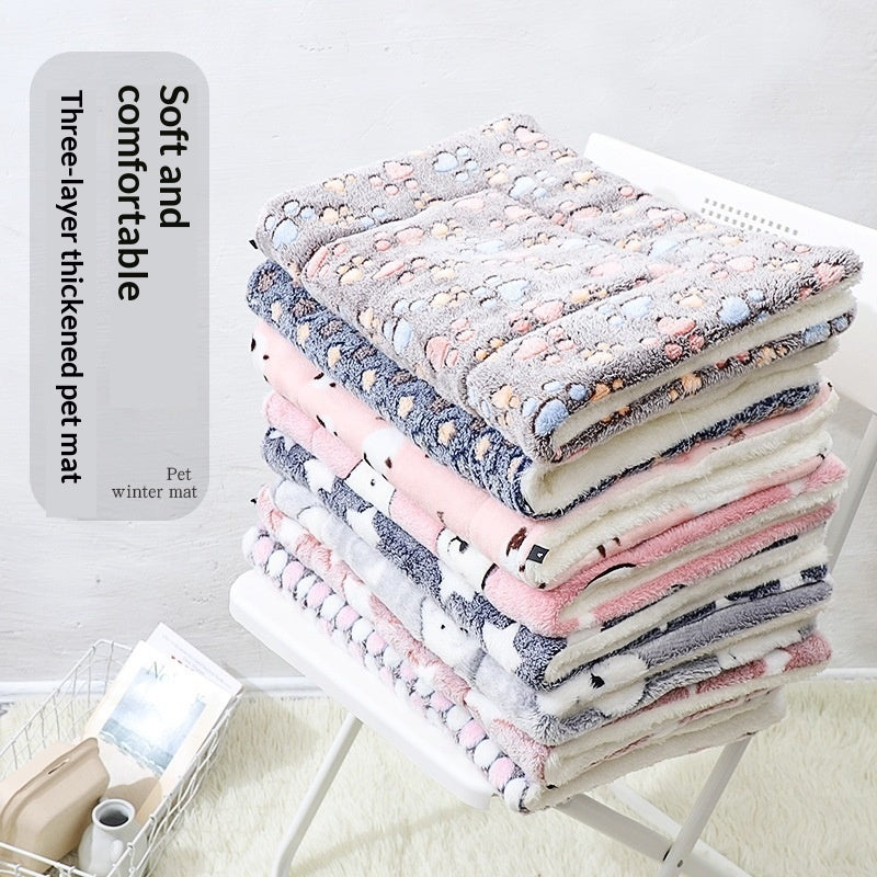 Folded pet mat stack in blue, pink, cream, and gray with paw prints