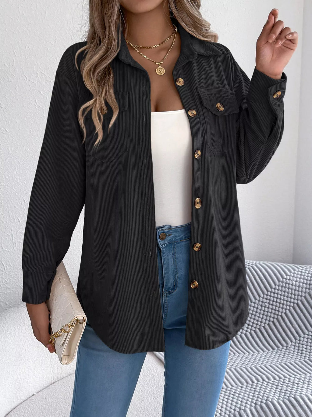 Black corduroy shacket with long sleeves, buttoned front, and two chest flap pockets.