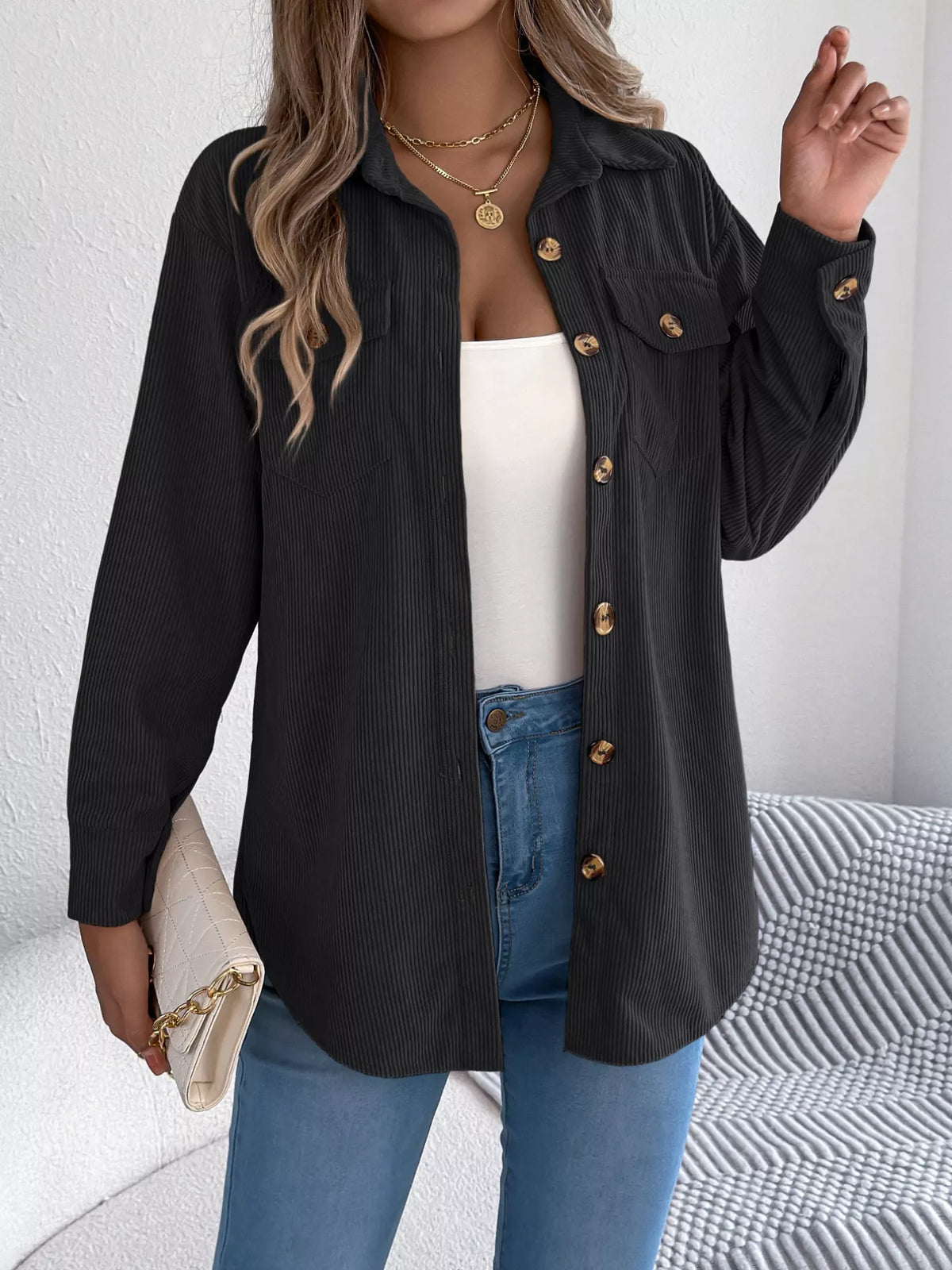 Black corduroy shacket with long sleeves, buttoned front, and two chest flap pockets.